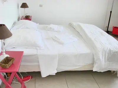 a white bed with white sheets and a red table at beautiful 4 bedroom villa, pool, Luberon in Cadenet