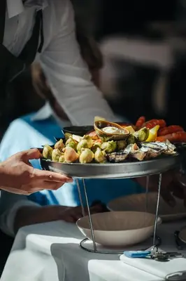 a person holding a tray of food on a table at La Bastide de Paula in Aix-en-Provence