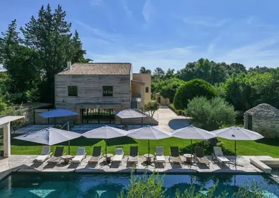 a pool with umbrellas and chairs and a house at Coeur des Hommes in Le Thor