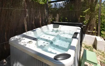 a bath tub sitting in a yard next to a fence at Maison Avec Jacuzzi in Mazan