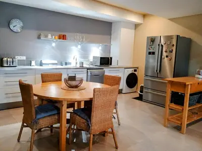 a kitchen with a table and chairs and a refrigerator at Spacieux 74 m2 Standing Clim & Parking Privé Centre Ville in LʼIsle-sur-la-Sorgue