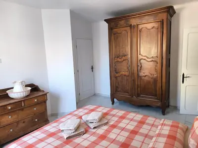 a bedroom with a wooden cabinet and a bed with two towels at Maison au coeur de Banon in Banon