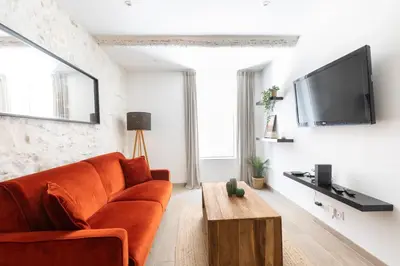 a living room with a orange couch and a tv at Le Cocon du Luberon - Clim - Wifi - Hypercentre in Apt