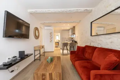 a living room with a red couch and a flat screen tv at Le Cocon du Luberon - Clim - Wifi - Hypercentre in Apt