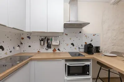 a kitchen with white cabinets and a counter top at Le Cocon du Luberon - Clim - Wifi - Hypercentre in Apt