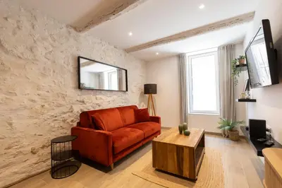 a living room with a red couch and a table at Le Cocon du Luberon - Clim - Wifi - Hypercentre in Apt