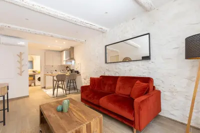 a living room with a red couch and a table at Le Cocon du Luberon - Clim - Wifi - Hypercentre in Apt