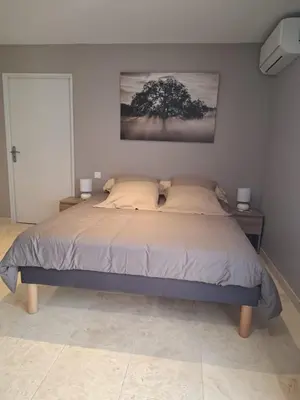 a bedroom with a bed with a tree on the wall at logement indépendant avec terrasse privative dans les Alpilles in Aureille