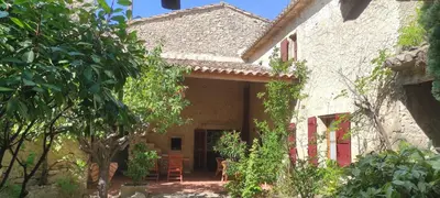 an external view of a house with chairs and trees at Maison de famille traditionnelle provençale in Gordes