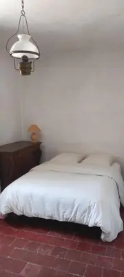 a bedroom with a white bed and a night stand at Maison de famille traditionnelle provençale in Gordes