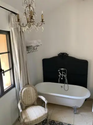 a bath tub in a bathroom with a chair and a chandelier at Peaceful Studio With Private Pool In Luberon in Ansouis