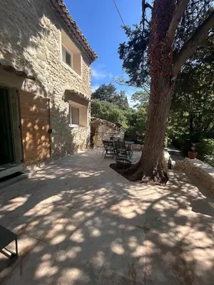 a patio with benches and a tree next to a building at La Maison Du Jas in Puyvert