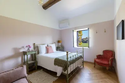 a bedroom with a bed and a chair and a window at Terres Élaïs in Robion en Luberon