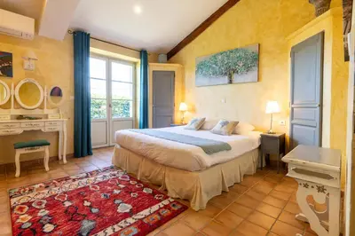 a bedroom with a bed and a large window at La Bastide des Amouriers in Caumont-sur-Durance