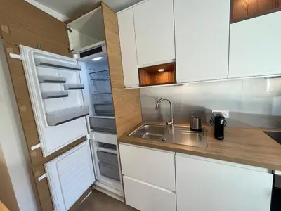 a kitchen with white cabinets and a sink and an open refrigerator at Le Nid des Cardeurs studio cosy centre historique in Aix-en-Provence