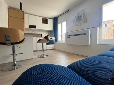 a bedroom with a blue bed and a kitchen at Le Nid des Cardeurs studio cosy centre historique in Aix-en-Provence