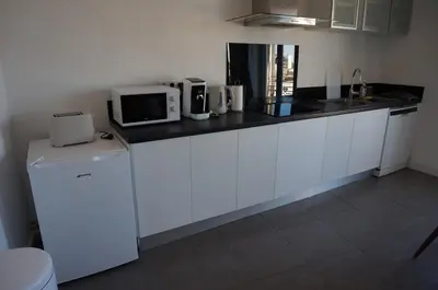a kitchen with white cabinets and a black counter top at Appart Suite Privilege XL avec Parking in Salon-de-Provence