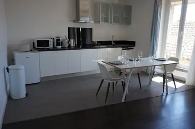 a white kitchen with a white table and chairs at Appart Suite Privilege XL avec Parking in Salon-de-Provence