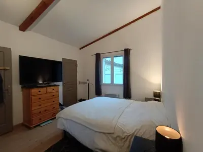 a bedroom with a bed and a dresser with a television at Maison villa avec piscine et spa, 8 à 10 personnes in LʼIsle-sur-la-Sorgue