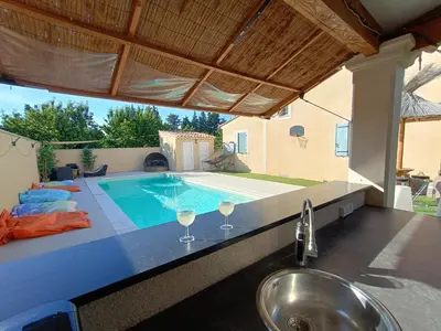 a kitchen with a sink and a swimming pool at Maison villa avec piscine et spa, 8 à 10 personnes in LʼIsle-sur-la-Sorgue