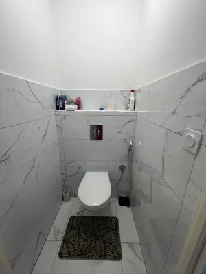 a white bathroom with a toilet and marble walls at Belle villa à Carpentras in Carpentras