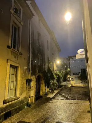 an empty street at night with a building at Charming house in the village center of Venasque in Venasque