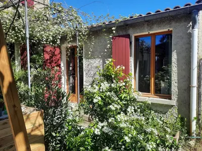 a house with red doors and a yard with plants at Petit studio avec jardin à 10 mn d'Avignon in Entraigues-sur-la-Sorgue