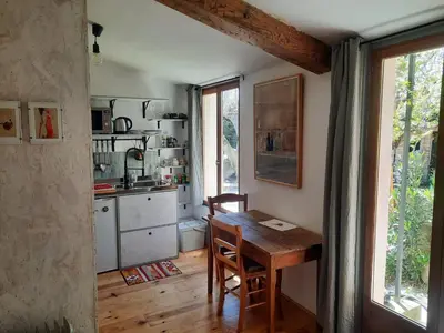 a kitchen with a wooden table and a window at Petit studio avec jardin à 10 mn d'Avignon in Entraigues-sur-la-Sorgue