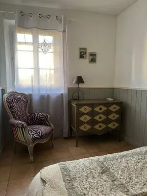 a bedroom with a chair and a dresser and a window at Maison au Cœur de Isle-sur-la-Sorgue in LʼIsle-sur-la-Sorgue