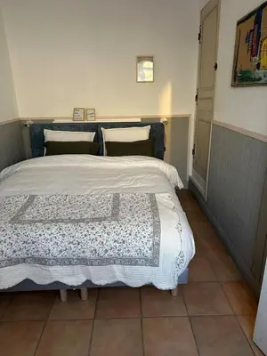 a bedroom with a bed with a white comforter at Maison au Cœur de Isle-sur-la-Sorgue in LʼIsle-sur-la-Sorgue