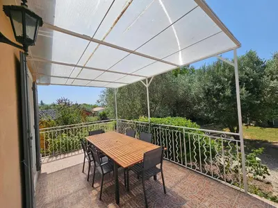 a patio with a table and chairs on a balcony at Villa de la Goutte d'Or in Caromb