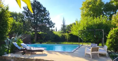 a swimming pool with two chairs and a table next to it at Chambre meublé Eden à Noves in Noves