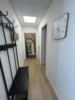 a hallway with a clock on a white wall at L'étape Aixoise - appartement climatisé terrasse centre ville Rotonde cours Mirabeau allées provençales in Aix-en-Provence