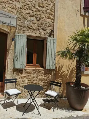a table and two chairs and a tree in front of a building at Trés jolie bastidon de village in Puyvert