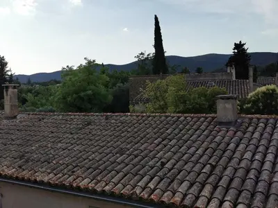 a tile roof of a house with mountains in the background at Trés jolie bastidon de village in Puyvert