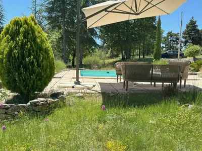 a patio with an umbrella and chairs and a pool at Le Bastidon in Caseneuve