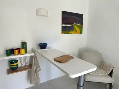 a white table and a chair in a room at Le Bastidon in Caseneuve
