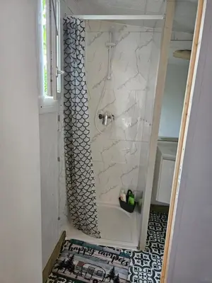 a shower in a bathroom with a white tile floor at Escapade en caravane près d'aix en provence in Meyreuil