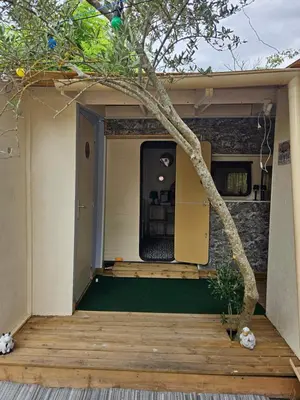 a house with a wooden porch with a tree at Escapade en caravane près d'aix en provence in Meyreuil