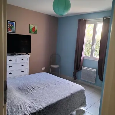 a bedroom with a bed and a tv and a window at L infiniment zen in Caromb