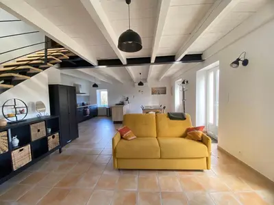 a living room with a yellow couch and a kitchen at Les Tilleuls in Bonnieux