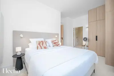 a white bedroom with a large white bed with pink pillows at Domaine Bellevue Ste-Victoire View Pools & Cinema in Le Puy-Sainte-Réparade