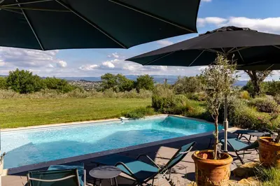 a swimming pool with chairs and an umbrella at La Tiny du Luberon in Pertuis