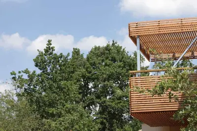a building with a wooden deck next to trees at La Source in Saint-Saturnin-les-Apt