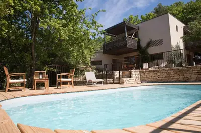 a swimming pool with chairs and a house at La Source in Saint-Saturnin-les-Apt
