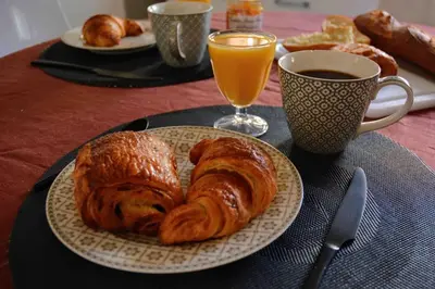 a plate with two croissants and a cup of orange juice at Large studio with terrace and air conditioning in Aix-en-Provence