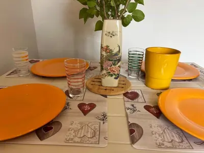 a table with orange plates and a vase on it at La maison aux oiseaux - Luberon in Oppède