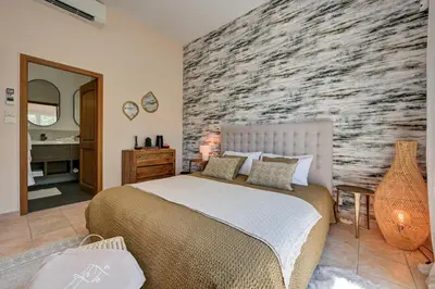 a bedroom with a large bed and a stone wall at La Villa KEF - Domaine & Golf de Pont Royal in Mallemort