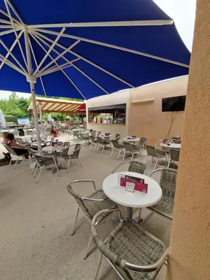 a group of tables and chairs with a blue umbrella at Mobil home en Provence - Camping 4 étoiles- 2 chambres -4 à 6 pers-clim-terrasse-TV in Cadenet