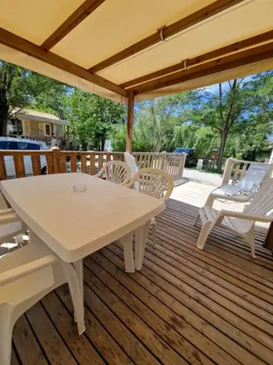 a wooden deck with a table and chairs on it at Mobil home en Provence - Camping 4 étoiles- 2 chambres -4 à 6 pers-clim-terrasse-TV in Cadenet